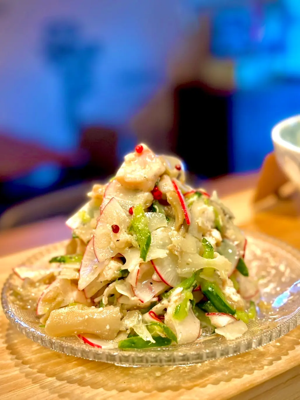 木のカウンターの上に置かれたガラスの皿に、低温調理した鶏ささみと玉ねぎやピーマン、ラディッシュなどの野菜を合わせたデリ風マリネが山のように盛られている料理の写真