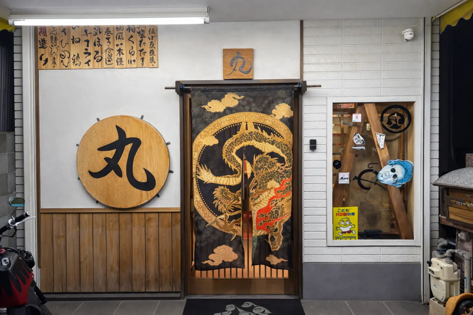 和洋創作居酒屋丸の店舗外観。格子戸の入口と店頭のメニュー看板、暖色の電球が並ぶ夜の雰囲気が伝わり、初めてでも入りやすい印象の写真